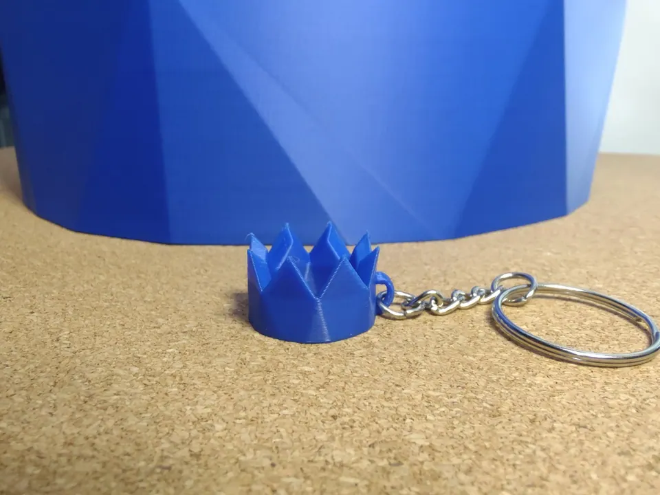 Blue keychain sitting beside a full-size blue party hat